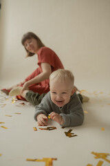 Mom and son rejoice at the holiday and lie on the floor. Happy mom and son throw gold tinsel. Holiday. Body positive