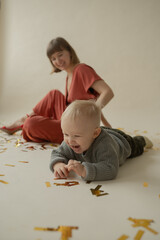 Mom and son rejoice at the holiday and lie on the floor. Happy mom and son throw gold tinsel. Holiday. Body positive