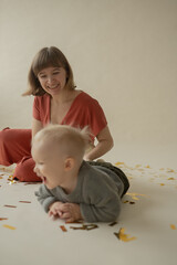 Mom and son rejoice at the holiday and lie on the floor. Happy mom and son throw gold tinsel. Holiday. Body positive