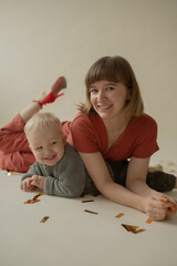 Mom and son rejoice at the holiday and lie on the floor. Happy mom and son throw gold tinsel. Holiday. Body positive