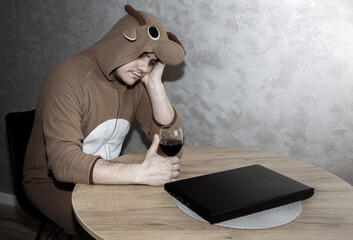Office worker in cosplay costume of a cow. Guy in the funny animal pyjamas near the a glass of...