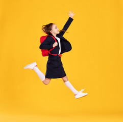 Excited schoolgirl jumping high in studio
