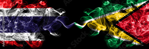 Thailand, Thai vs Guyana smoky mystic flags placed side by side. Thick colored silky abstract smokes flags.