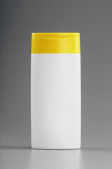 White plastic bottle with yellow cap with shampoo gel on gray background