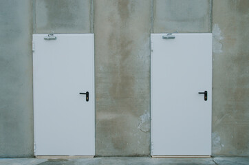 Dos puertas blancas en muro de cemento