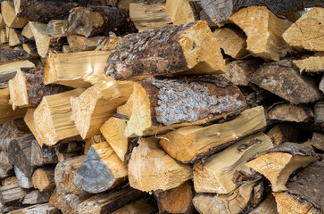 Pile of weathered and fresh spruce and pine firewood. The growth rings on the logs creates patterns.
