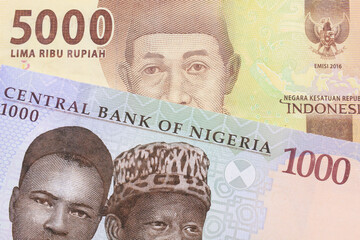 A macro image of a blue, purple and green one thousand  naira note from Nigeria paired up with a orange five thousand Indonesian rupiah note.  Shot close up in macro.