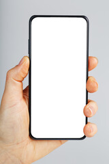 Hand holds black smartphone with blank white screen and modern frameless design isolated on gray background.