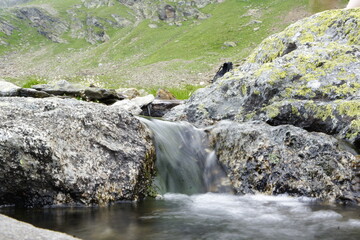 Wasser fließt über Steine einen Bergbach hinunter 