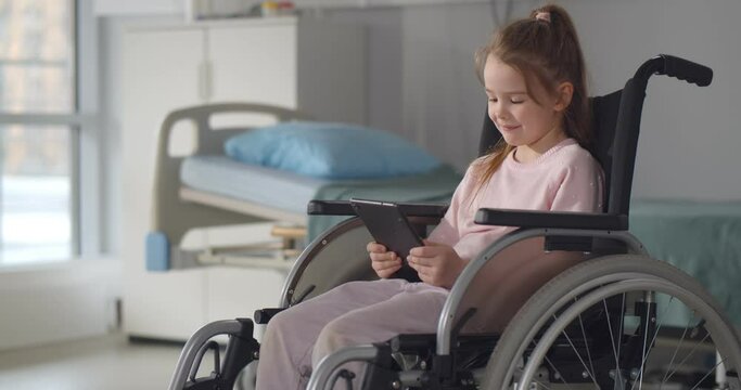 Preteen girl with tablet in wheelchair at hospital ward