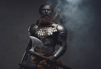 Muscular mythical soldier holding an axe and staring at camera in fog