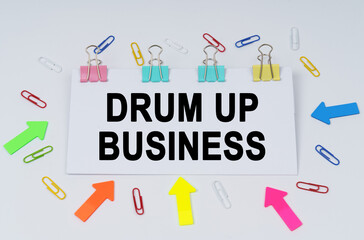 On the table there are paper clips and directional arrows, a sign that says - Drum Up Business