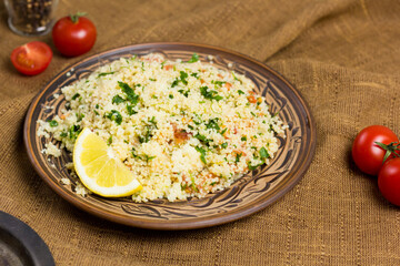 Traditional Arabic salad or Tabbouleh on ceramic plate, healthy vegetarian dish with couscous, tomatoes, parsley, mint