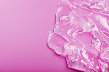 Transparent liquid gel on a pink background with free space.