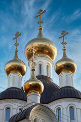 Fototapeta na wymiar Golden domes and crosses of the Christian church against the blue sky