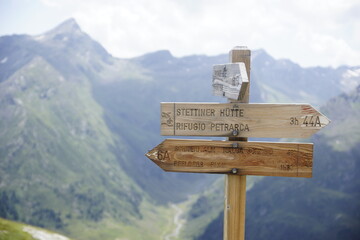 Wegweiser in den Alpen für Wanderwege zur Stetiger Hütte, Schneid Alm vor dem Alpenpanorama