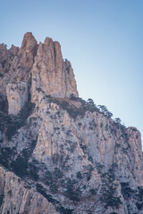 High mountains with forested slopes and peaks on blue sky background