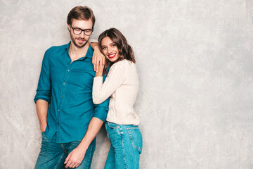 Smiling beautiful woman and her handsome boyfriend. Happy cheerful family having tender moments near grey wall in studio.Pure cheerful models hugging.Embracing each other