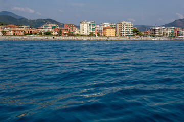 Fototapeta premium Seascape with azure water in the foreground and Italian port city in the background