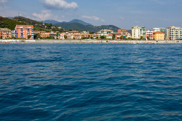Fototapeta na wymiar Seascape with azure water in the foreground and Italian port city in the background