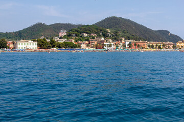 Seascape with azure water in the foreground and Italian port city in the background