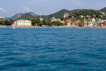 Fototapeta premium Seascape with azure water in the foreground and Italian port city in the background