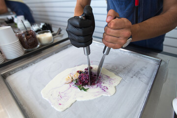 Stir-fried ice cream rolls at freeze pan. Rolled ice cream, hand made ice cream dessert. Fried ice cream machine with steel chilled pan.