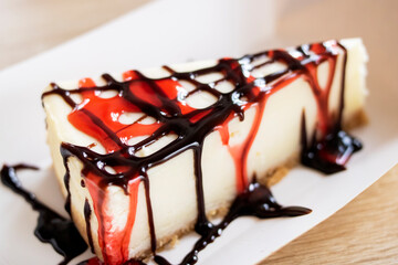 Cheesecake with raspberry and chocolate syrup on wooden table