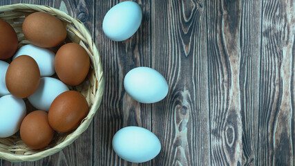 several fresh chicken eggs in a straw basket on a wooden background. Healthy eating concept