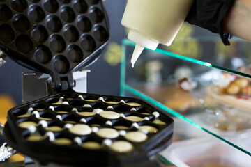 .Pouring dough on waffle maker. Preparing Hong Kong waffle