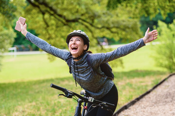 Happy woman cyclist driving through  the public park