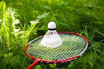 Shuttlecock and badminton racket lie on the green grass. Summer sunny day. Concept healthy lifestyle. Lifestyle, vacation, sport and fun.