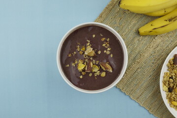 Brazilian açai in a white bowl with banana, granola and chestnuts. Top view. 