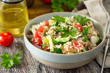 Food dieting concept, tuna salad close-up. Couscous salad with conserved tuna, tomatoes, cucumbers and purple onions on rustic wooden table.