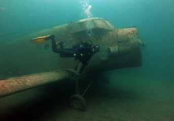 Diver with wreck of Antonow An-2 plane under water in Zakrzowek - articial lake in Cracow, Poland