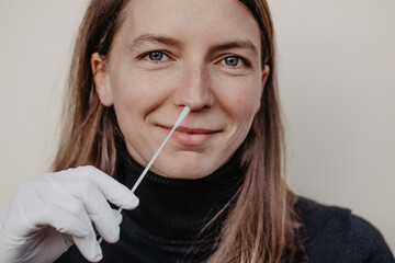 Frau hält Teststäbchen mit Handschuh in der Hand um Antigentest auf Coronaviren zu Hause...