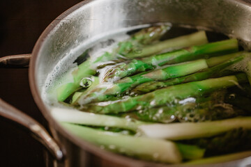 Grüner Spargel kocht in Kochtopf aus Edelstahl zur Spargelsaison