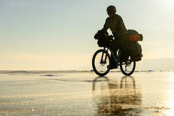 Fototapeta na wymiar Byciclist on Baikal lake in winter on the sunset. Irkutsk Region, Russia