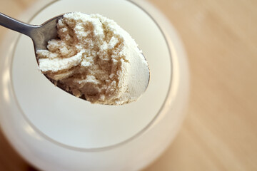 Putting whey protein powder into a glass of water with a spoon