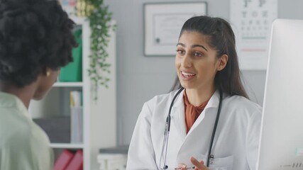 Female doctor or consultant wearing white coat having meeting with female patient in office - shot in slow motion - Powered by Adobe