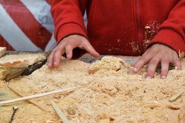 Child's hands on the background of a handful of dry technological chips. Selective focus. Remains of woodworking, untreated wood,