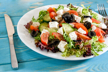 Greek salad on a plate of vegetables with a leaf of salad