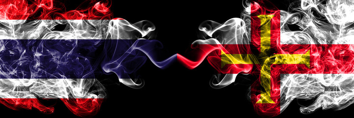 Thailand, Thai vs United Kingdom, Great Britain, British, Guernsey  smoky mystic flags placed side by side. Thick colored silky abstract smokes flags.