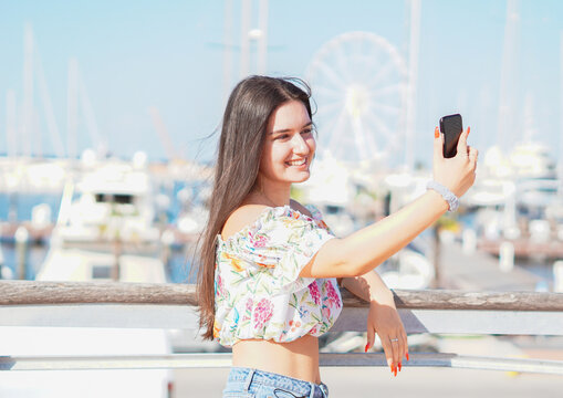 Teenager taking selfie at beach - Young girl holding smartphone camera to take a picture of herself during her summer vacations