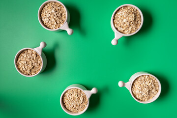 Top view of oat in the bowls over green background, with copy space,