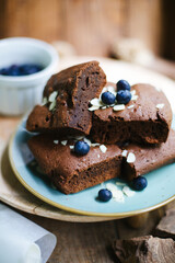 sliced brownies garnished with blueberries. pieces of chocolate cake on a plate. chocolate pie close-up.