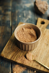 cocoa powder in a small bowl. cocoa powder on a wooden board. blank for baking. ingredient for a pastry chef. cocoa in a golden spoon
