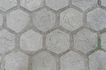 abstract background of tiled walkway in the park with grass punching between the joints close up