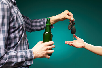 A man with bottle beer giving a car key to someone for driving the car.Do not drink and drive! Drunk driving. Drink and auto keys.