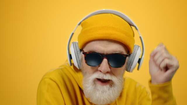 Happy Senior Man Using Headphones Inside. Old Guy Moving To Music Indoors.